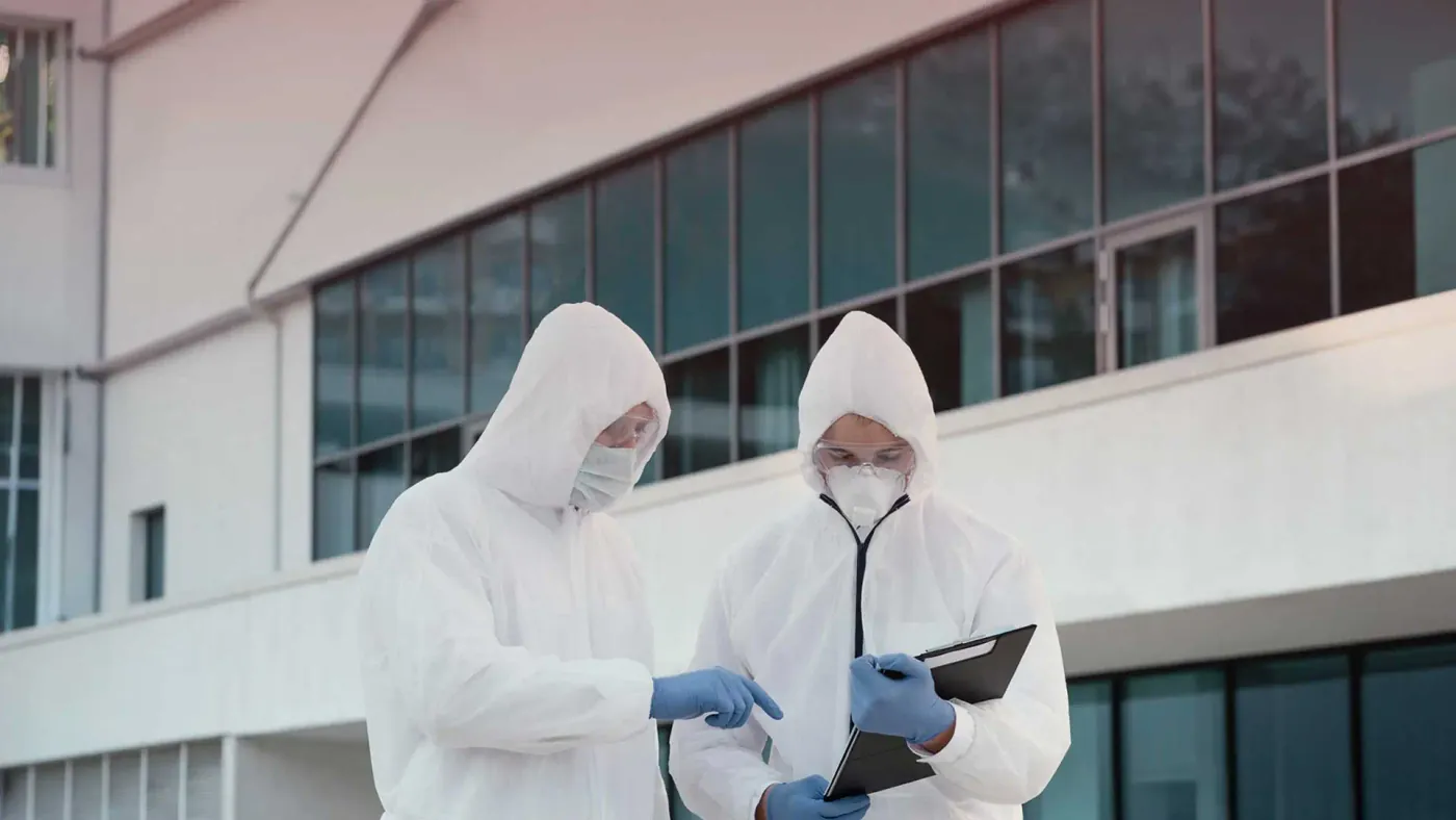 Two pest control technicians in protective suits assessing a commercial property in Iowa.